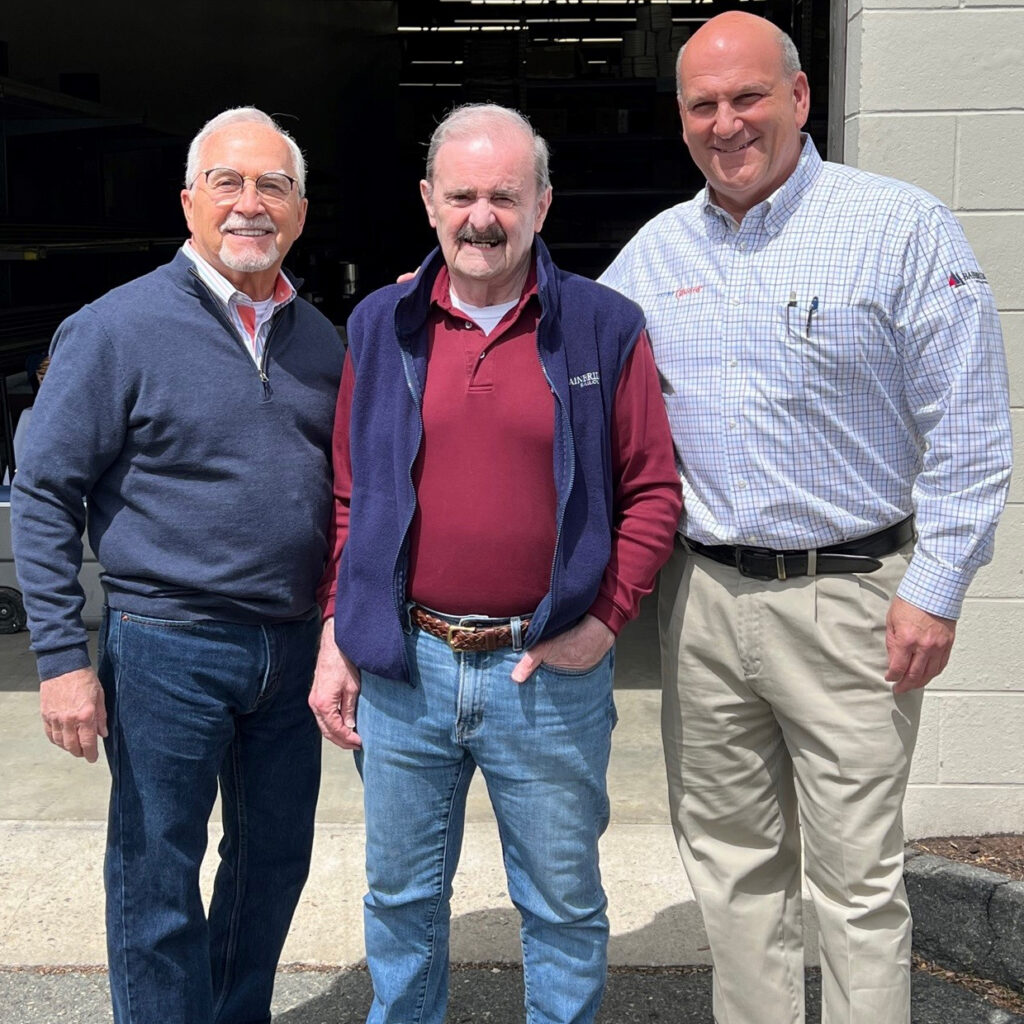 Three men standing next to each other in front of a building.